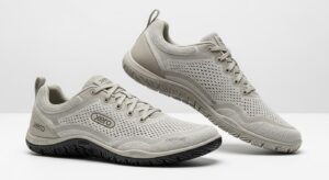 A pair of light grey Xero Shoes featuring mesh uppers, lace closures, and textured rubber soles. Designed for walking, they deliver all-day comfort with ventilation holes and a minimalistic style. The "Xero" brand name is displayed on the shoes.